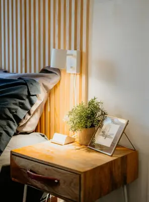 a wooden table with a plant on it next to a bed at Private room with private bathroom and backyard in Brooklyn