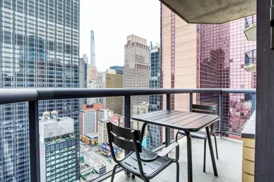 a table and chairs on a balcony with a city skyline at Midtown 1br w gym elevator nr Rockefeller Ctr NYC-1401 in New York