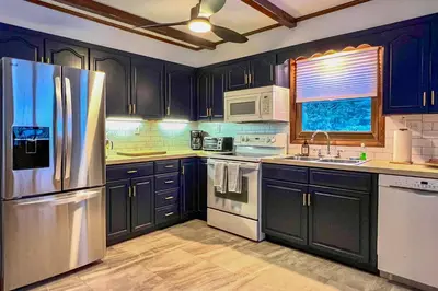 a kitchen with black cabinets and a stainless steel refrigerator at Vacation Rental Home about 2 Mi to Windham Mountain! in Windham