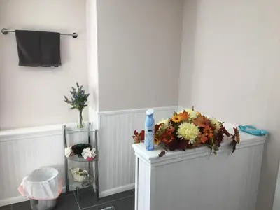 a white bathroom with a flower arrangement on a shelf at Privacy, entertainment, comfort galore 2 BR LR 1BA Home Theater, Pool Table in Suffield