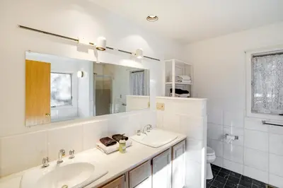 a white bathroom with two sinks and a mirror at Great Barrington Lakeside Getaway with Kayak and Grill in Great Barrington