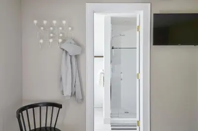 a bathroom with a mirror and a black chair at The Kent Collection - The Firefly Inn in Kent