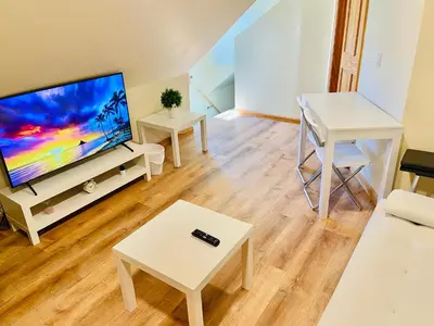 a living room with a flat screen tv and a table at Bright, Stylish & Cozy Private Attic Unit near NYC! in Haledon