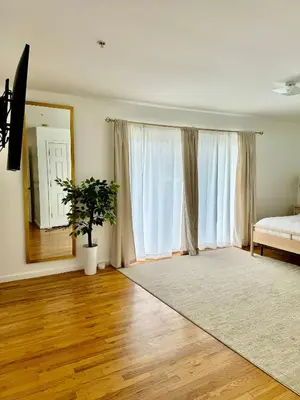 a living room with a bed and a mirror at Stylish Evergreen Apartment By Newark Airport in Newark