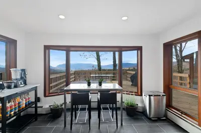 a kitchen with a table and chairs and windows at 5 Star Gorgeous Cliffside Chalet with Panoramic Views in Tannersville