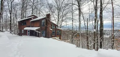 a log cabin in the woods in the snow at 5 Star Gorgeous Cliffside Chalet with Panoramic Views in Tannersville