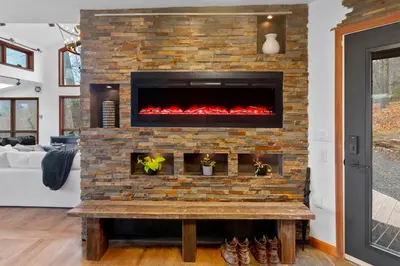 a living room with a brick fireplace at 5 Star Gorgeous Cliffside Chalet with Panoramic Views in Tannersville