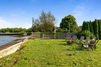 a group of chairs sitting in the grass by the water at Piermont Waterfront Villa with Hot Tub in Piermont