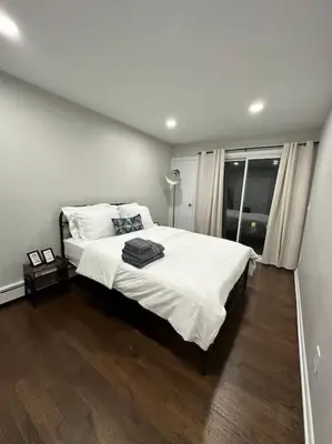 a bedroom with a large bed with white sheets at Cozy 2 BR suite, 10 min to NYC &Times Sq in West New York