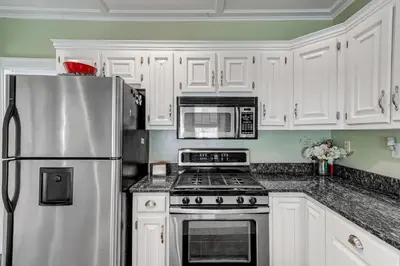 a kitchen with white cabinets and a stainless steel refrigerator at Charming Connecticut Retreat Near Museums and Hiking in Waterbury