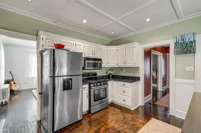 a kitchen with white cabinets and a stainless steel refrigerator at Charming Connecticut Retreat Near Museums and Hiking in Waterbury