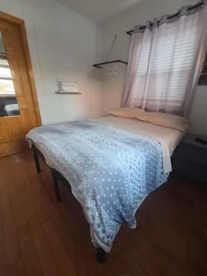 a bedroom with a bed with a blue blanket and a window at New York in Woodside