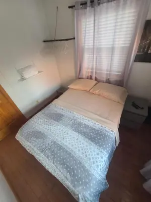 a small bed in a room with a window at New York in Woodside