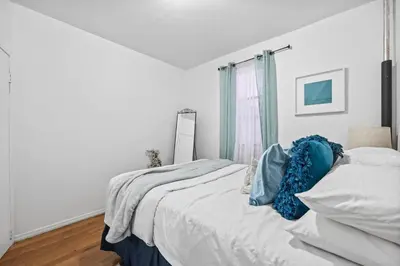 a bedroom with a bed with white sheets and blue pillows at 1BR Apt Walk to Central Park and Columbia University in New York