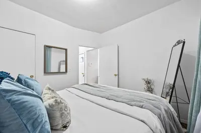 a white bedroom with a bed with blue pillows at 1BR Apt Walk to Central Park and Columbia University in New York