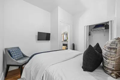 a white bedroom with a bed and a chair at 2BR Apt Walk to Restaurants & Time Square in New York