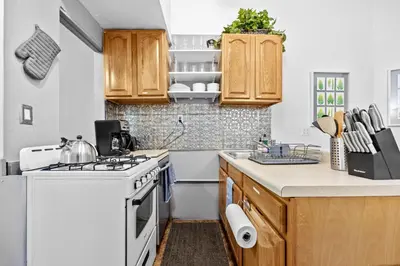 a kitchen with wooden cabinets and a white stove top oven at 2BR Apt Walk to Restaurants & Time Square in New York