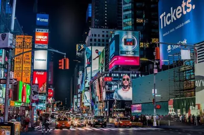 a busy city street at night with cars and buildings at 2BR Apt Walk to Restaurants & Time Square in New York