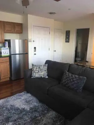 a living room with a couch and a stainless steel refrigerator at Lovely one bedroom with free parking in Schenectady