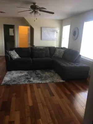 a living room with a black couch and wooden floors at Lovely one bedroom with free parking in Schenectady