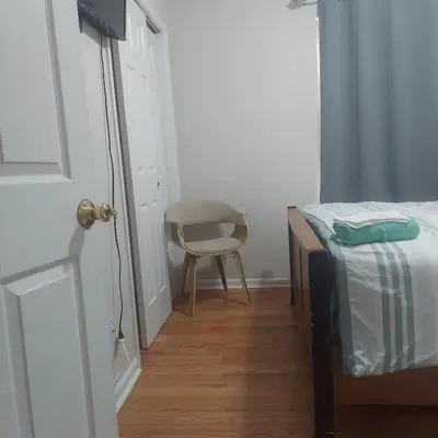 a bedroom with a bed and a chair next to a door at Cosy Bedroom 12mins to Airport Prudential NJIT UMDJ Penn Station in Newark