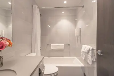a white bathroom with a tub and a toilet at The Melrose Hotel in Bronx