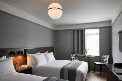 a hotel room with two beds and a table at The Melrose Hotel in Bronx