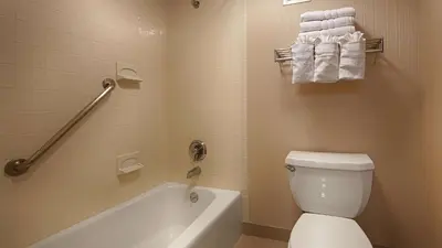 a bathroom with a tub and a toilet and towels at Best Western Springfield West Inn in West Springfield