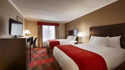 a hotel room with two beds and a flat screen tv at Best Western Springfield West Inn in West Springfield