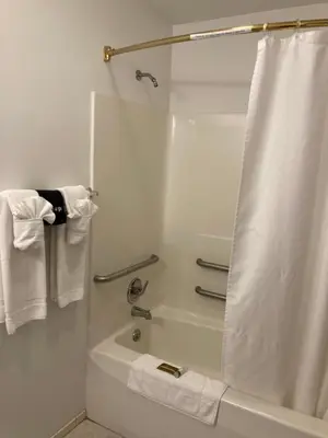a bathroom with a tub and a shower with towels at The Hotel Pratt in Cooperstown