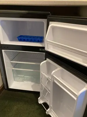 an empty refrigerator with its door open with a blue drawer at The Hotel Pratt in Cooperstown