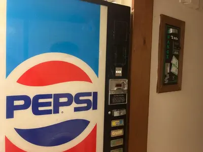 a pepsi soda machine is next to a wall at The Hotel Pratt in Cooperstown