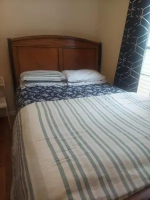 a bed with a wooden headboard and a white pillow at Crystal Room 1 Guest House near 12mins to EWR airport / Prudential / NJIT / Penn station in Newark