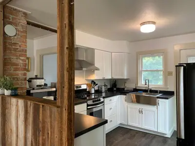 a kitchen with white cabinets and a black refrigerator at Water Street Apartments in Williamstown