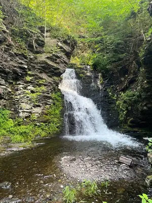 a waterfall on the side of a mountain next to a creek at The Flying Dutchman Cottage in amenities filled Masthope community Ski Big Bear in Lackawaxen