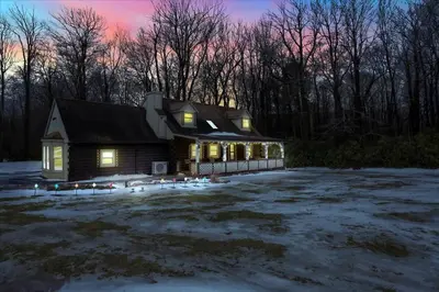 a house with lights on in a yard with snow at Cabin in Long Pond Gameroom Pool Table in Long Pond