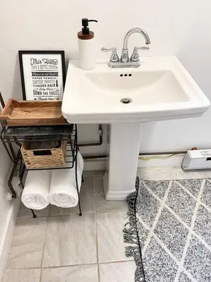 a bathroom with a white sink and a shelf with towels at Catskills Quaint Cottage with Peloton Minutes from Hiking in Mount Tremper
