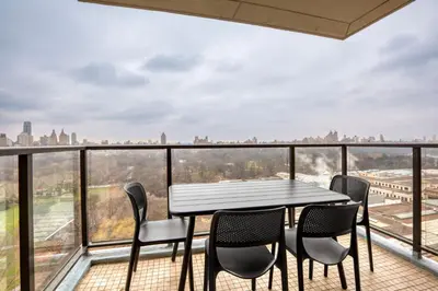 a table and chairs on a balcony with a view of the city at Blueground UES gym balcony nr central park NYC-1404 in New York