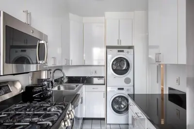 a white kitchen with washing machines and a sink at Blueground UES gym balcony nr central park NYC-1404 in New York
