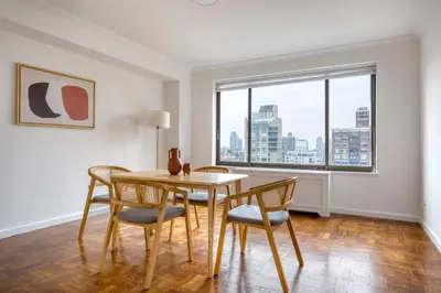 a dining room with a table and chairs and a window at Blueground UES gym balcony nr central park NYC-1404 in New York
