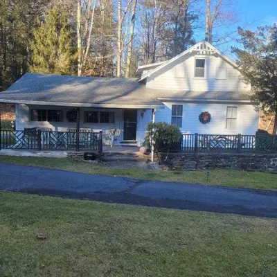 a white house with a fence in front of it at Panther Mountain Lodge in Phoenicia