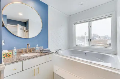 a bathroom with a large tub and a mirror at Bright Milford Beach House with Outdoor Shower in Milford