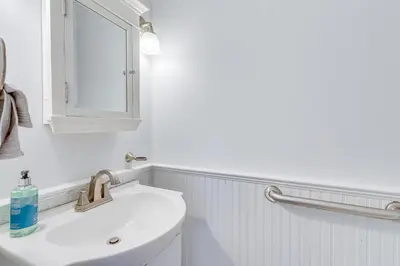 a white bathroom with a sink and a mirror at Bright Milford Beach House with Outdoor Shower in Milford