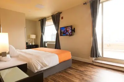 a bedroom with a bed and a large window at Romana Hotel - NYC in Queens