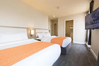 two beds in a hotel room with a flat screen tv at Romana Hotel - NYC in Queens
