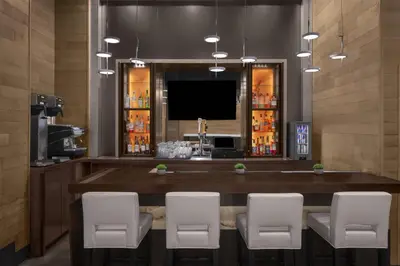 a bar with white chairs and a flat screen tv at Cambria Hotel New York - Chelsea in New York