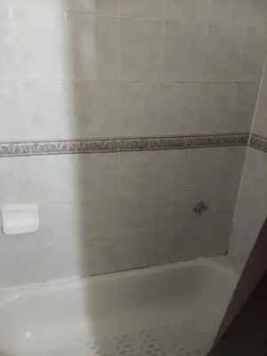 a bathroom with a bath tub with a tiled floor at Deluxe Room A 12 minutes to Ewr in Newark