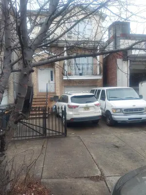 two cars parked in a parking lot in front of a house at Deluxe Room A 12 minutes to Ewr in Newark