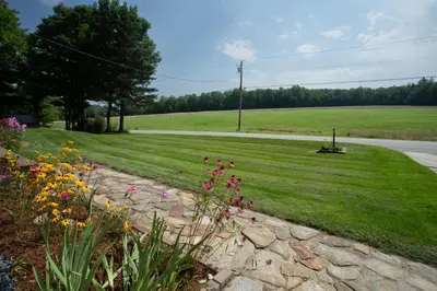 a garden with flowers on the side of a road at 14mi to Mt. Snow! Arcade, Private Suite, King Bed! in Whitingham