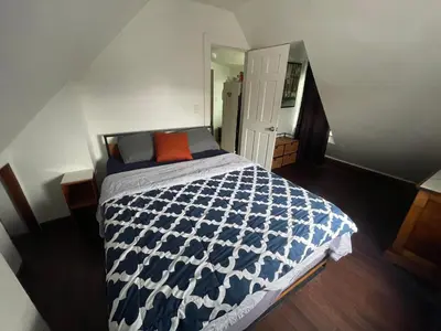 a bedroom with a blue and white bed with an orange pillow at Private Loft 5 min away from LGA in East Elmhurst
